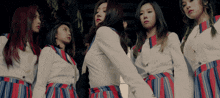 a group of girls are standing next to each other in striped skirts
