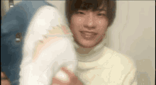 a man in a white turtleneck sweater is holding a stuffed shark .