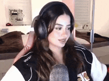 a woman wearing headphones is sitting in front of a microphone in a room .