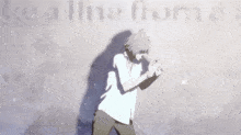 a man in a white shirt is standing in front of a gray wall
