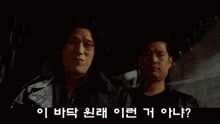 two men are standing next to each other in the rain in a movie .