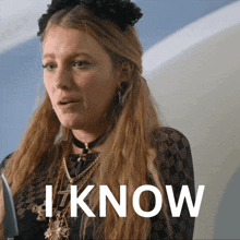 a woman with long blonde hair is wearing a choker and necklaces and the word i know is behind her