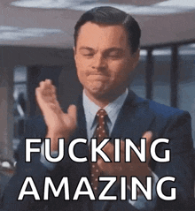 a man in a suit and tie is clapping his hands with the words fucking amazing below him .