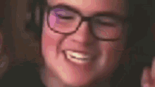 a close up of a person wearing glasses and headphones smiling .