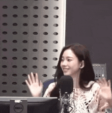 a woman sitting in front of a dell computer waving her hand