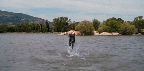 a man runs along the water and then falls in