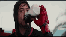a man in boxing gloves is drinking from a cup