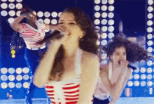 a woman is singing into a microphone while another woman looks on
