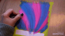 a person is drawing a pink and blue painting on a piece of paper that says made in animotica on the bottom