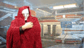 a man in a red robe with a hood is standing in a futuristic room