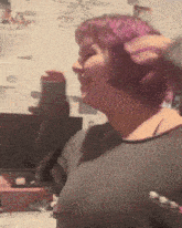 a woman with purple hair is standing in front of a computer monitor