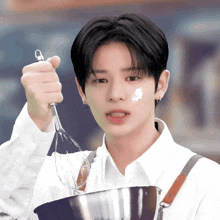 a young man is holding a whisk and a bowl of food
