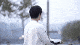 a man in a white shirt is standing on a balcony looking at the water .