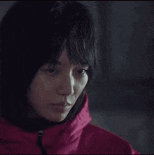 a close up of a woman wearing a pink jacket with a hood .