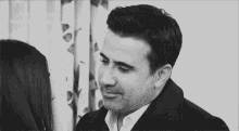 a black and white photo of a man and woman looking at each other .