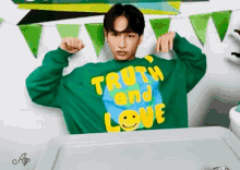 a man is wearing a green sweater that says truth and love