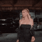 a woman wearing a headband and hoop earrings is standing in a parking garage