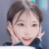 a close up of a young woman 's face with her hands on her face