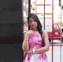 a woman in a pink and white floral dress is standing in front of a mirror