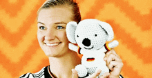 a woman is smiling while holding a stuffed koala bear