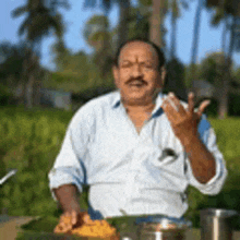 a man with a mustache is standing in front of a table with a tray of food .