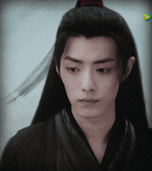 a young man with long black hair is wearing a black shirt