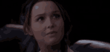 a close up of a woman 's face while sitting in a dark room .
