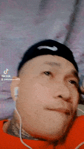 a man wearing headphones and a nike hat is making a funny face ..