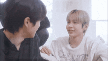 two young men are sitting next to each other on a couch and talking to each other .