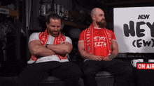 two men sit in front of a sign that says hey ( ew )