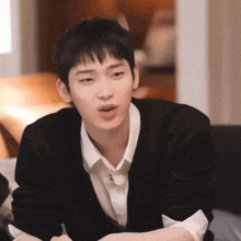 a young man wearing a black sweater and a white shirt