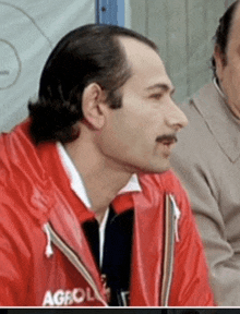 a man wearing a red jacket that says agevol on it