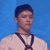 a young man wearing a white shirt and black tie is standing in front of a blue wall .