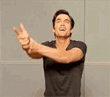 a man in a black shirt is standing with his arms outstretched and screaming .