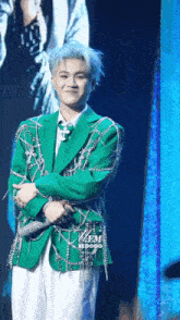 a man in a green jacket with chains around his sleeves is standing in front of a blue wall