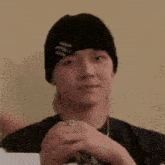 a young man wearing a black beanie and a ring