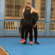 a man in a black tank top is wrestling another man