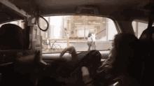 a woman is sitting in the driver 's seat of a car and looking out the window .