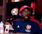 a man wearing a blue jacket and a red hat is sitting at a table .