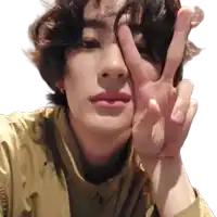 a young man is making a peace sign with his hands over his face .