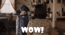 a woman is standing next to a boy who is wearing a bow tie and a hat and the word wow is on the bottom