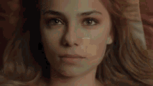 a close up of a woman 's face with a red pillow in the background