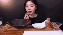 a woman is sitting at a table eating food with a spoon .