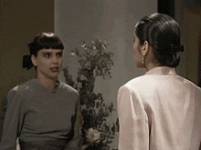 two women are standing next to each other and talking