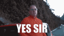 a man in a red sweater is giving the middle finger in front of a sign that says yes sir