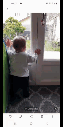 a baby is standing in front of a door and looking out