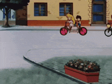 a girl and a boy are riding a bike down a street in front of a building