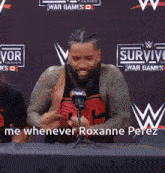 a man is sitting at a table with a microphone in front of a sign that says survivor