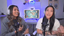 two women are talking into microphones in front of a computer