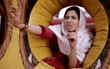 a woman wearing a white head scarf is sitting in a yellow and red circle